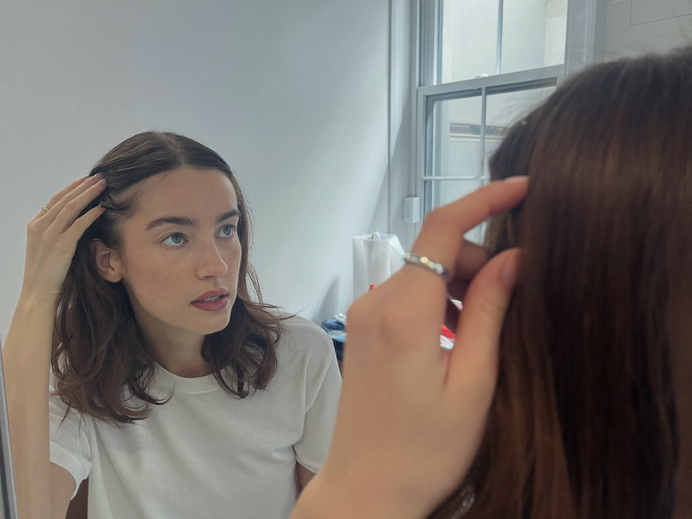 Woman examining her hair part in the mirror